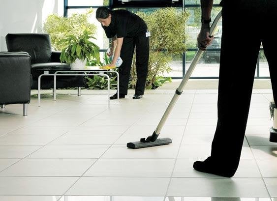 Professional cleaners maintaining a commercial space, vacuuming floors and tidying furniture, highlighting Route 9 Cleaning Services' commitment to cleanliness and attention to detail.