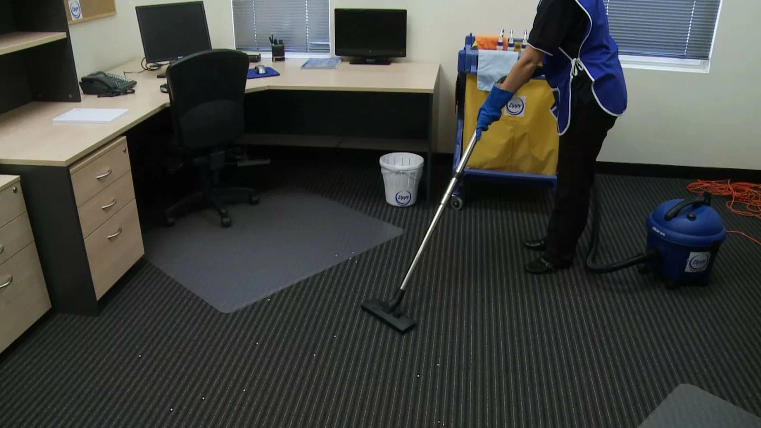 Professional cleaner using a vacuum in a modern office setting, highlighting commercial cleaning services for a spotless workspace.